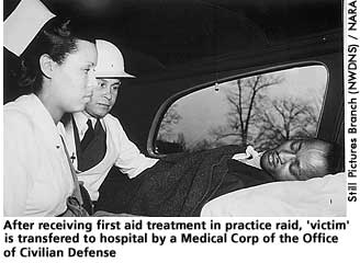[picture: Practice air raid 'victim' is transfered to  hospital by a Medical Corps of the Office of Civilian Defense.]  